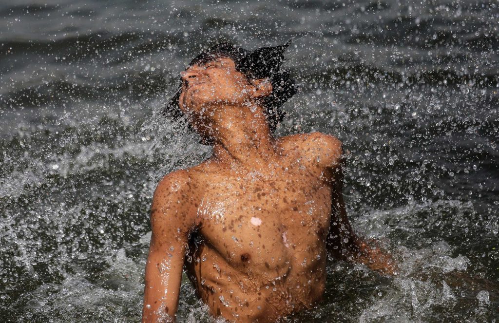 Indian youth jumps in Sabarmati river as they refresh themselves from heat on a hot afternoon, in Ahmedabad.